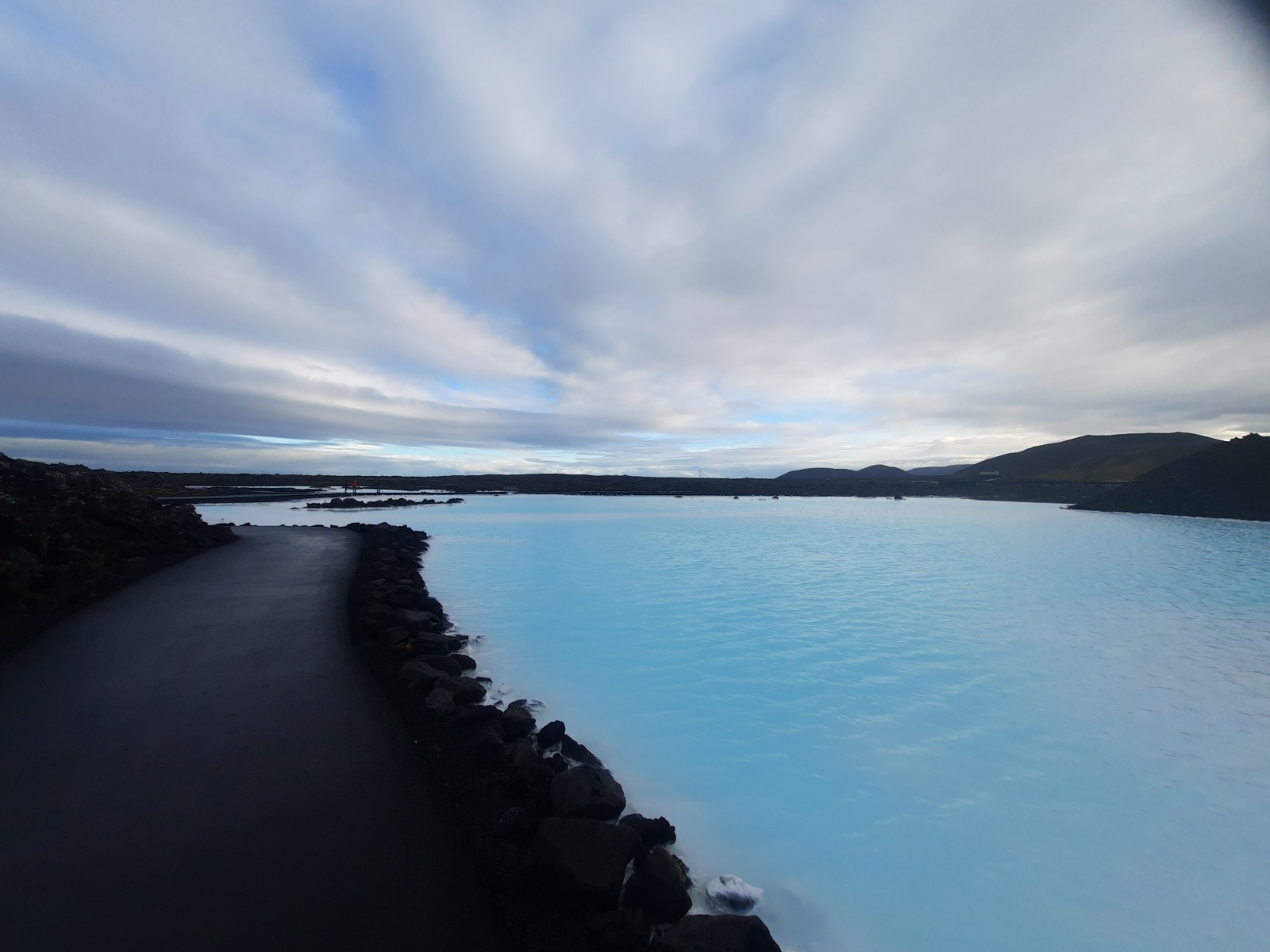 Black rocks surrounding a blue pool