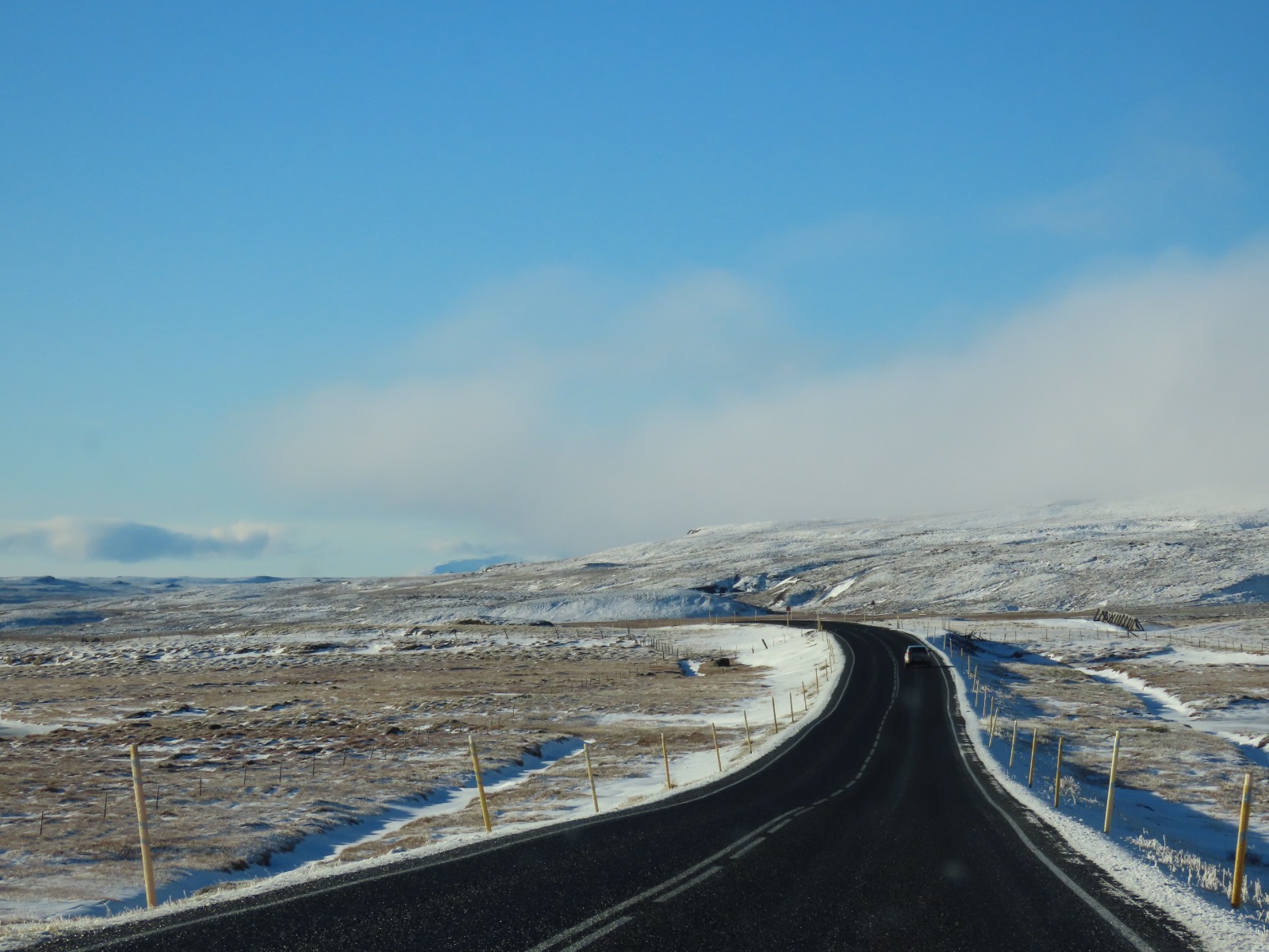 black road going through a with powder snow covered landscape