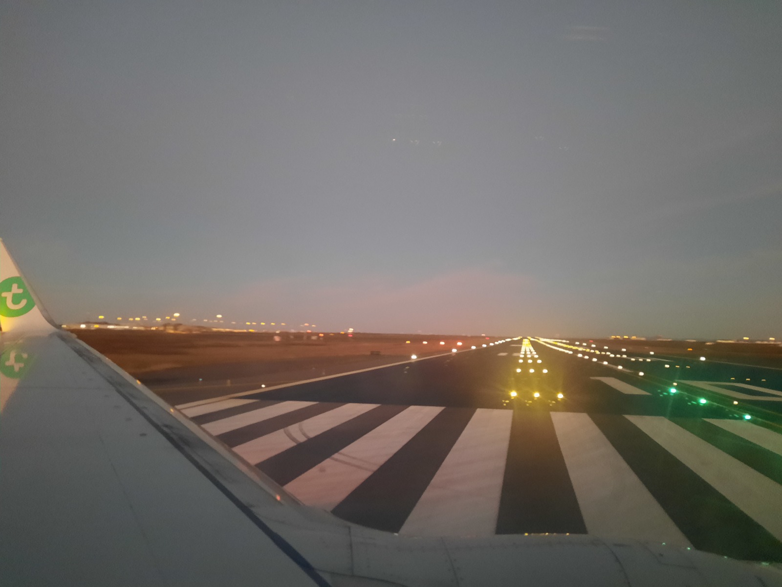 part of a plane wing with lighted runway