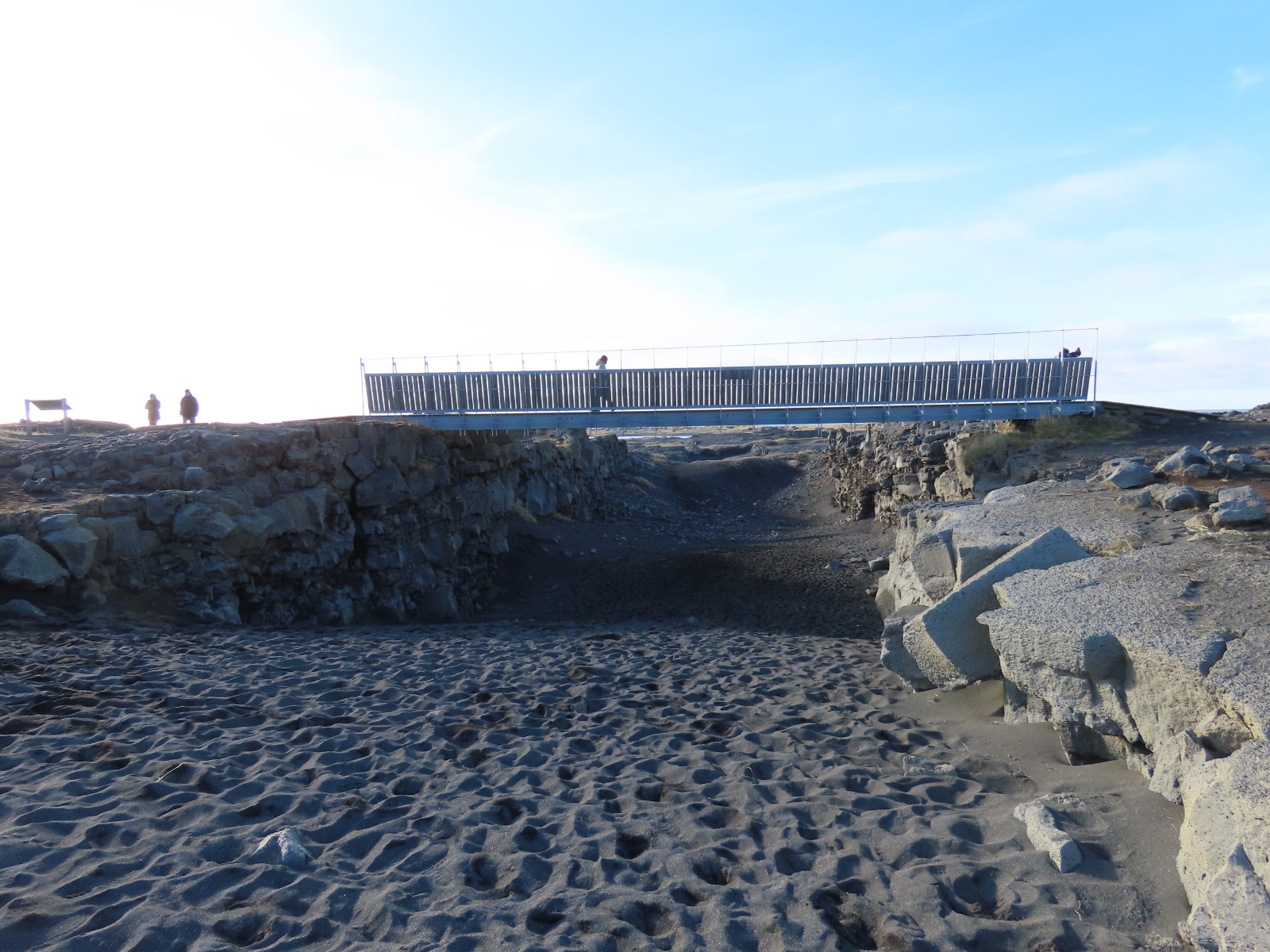 Iron bridge connecting two rock walls with blacksand between them